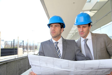 Architects checking construction site with plan outside