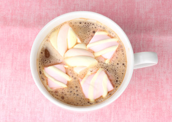 Cup of cappucino with marshmallows on pink background