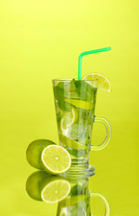Glass of cocktail with lime and mint on green background