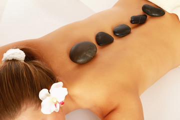 Pretty woman receiving a therapy with hot stones in spa center
