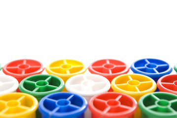 Colourful bobbins with shallow depth of field on white.