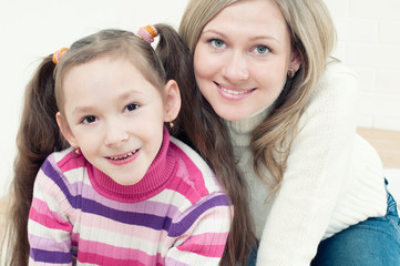 Pretty young woman and her little girl looking at camera