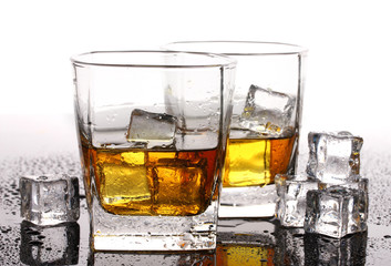 two glasses of scotch whiskey and ice on table isolated on white