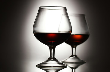 Two glasses of cognac on grey background