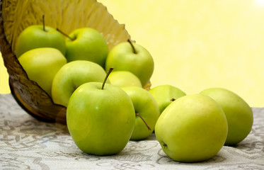 green apples in a glass vase on the table cloth