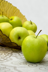 green apples in a glass vase on the table cloth
