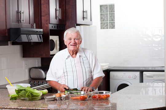 Happy Senior Man Preparing Food In Home Kitchen