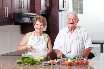 happy senior couple cooking in home kitchen