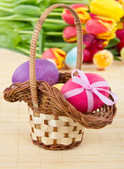 Fototapeta na wymiar Easter eggs in basket with tulips on background