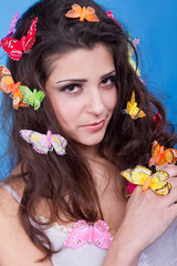 Beautiful girl with butterflies in hair isolated on blue