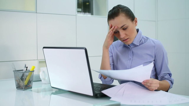 Young businesswoman overwhelmed by too much paperwork in office