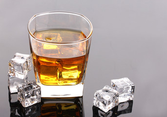 glass of scotch whiskey and ice on grey table