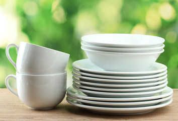 Clean dishes on wooden table on green background