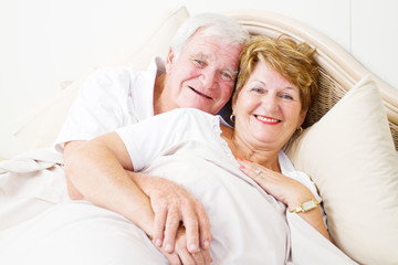 happy senior couple hugging in bed
