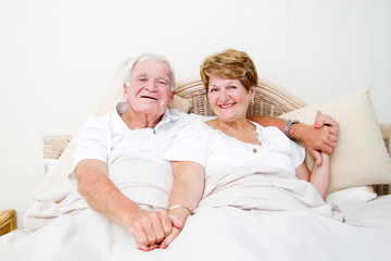 happy senior couple in bed relaxing