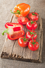 Fresh tomato, paprika and vintage wooden cutting board on canvas