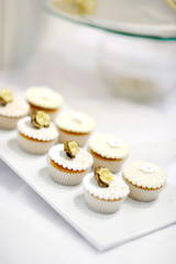 Decorated white vanilla cream cupcakes on a white plate