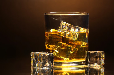 glass of whiskey and ice on brown background