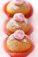 Drei Cupcakes mit Sahne und Puderzucker verziert