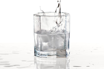 Glass of water and ice with splash on a white background