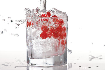 Glass of water, ice and red cranberries with splash