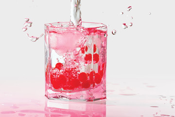 Glass of water, ice and red cranberries with splash