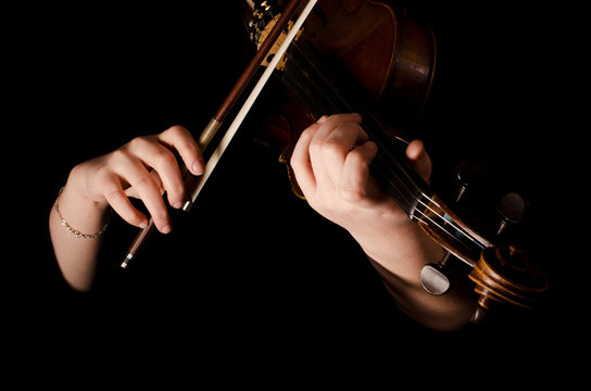 Female hands play a violin on the black