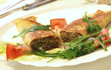 Rolled pancakes garnished with salad for dinner