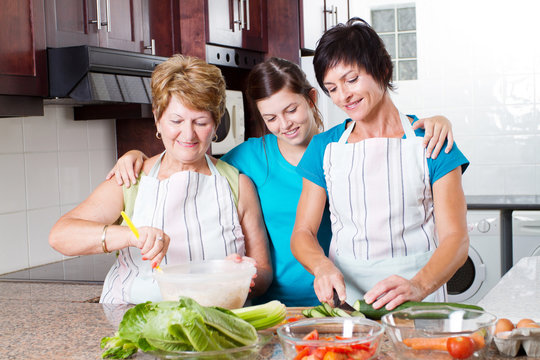 Teen Girl Watching Mother And Grandmother Cooking In Kitchen