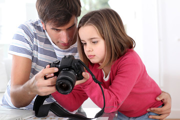 Father teaching little girl how to use camera