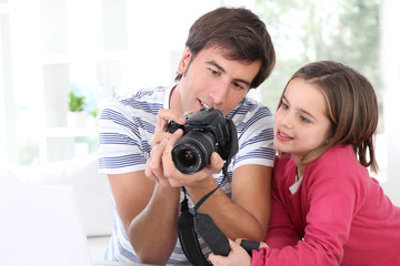 Father teaching little girl how to use camera