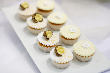 Decorated white vanilla cream cupcakes on a white plate