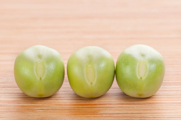 Three fresh green peas on wooden background