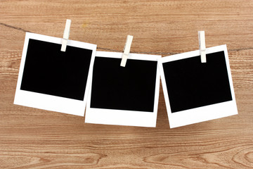 Photo papers hanging on the clothesline on wooden background