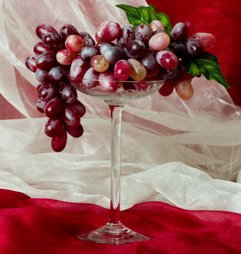 Beautiful red grape in glass on red background