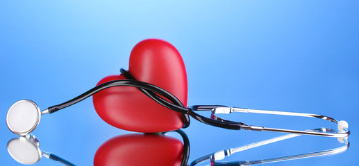 Medical stethoscope and heart on blue background