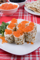 Rolls from pancakes with red caviar on a plate