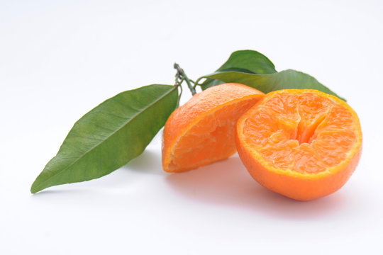 Mandarino tagliato a metà con foglie su sfondo bianco