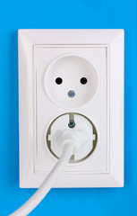 White electric socket with plug on the wall