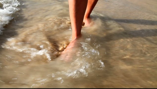 Beautiful women's feet in the surf