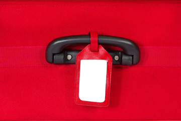 blank identification tag over red suitcase with handle