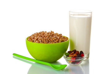 Boiled buckwheat in a green bowl a glass of milk isolated