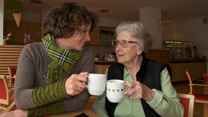 Seniorin und junge Frau beim Kaffee trinken