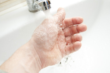 Washing of hands under the crane with water