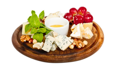 Various types of cheese with honey, nuts and grapes on plate, is