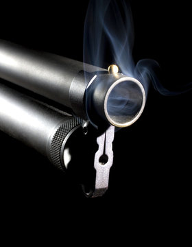 Hot shotgun muzzle billowing smoke on a black background