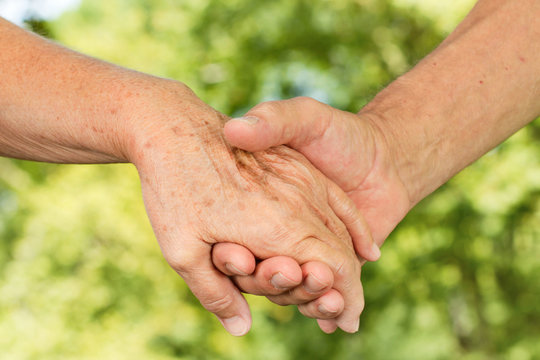 Closeup of old people hands holding together