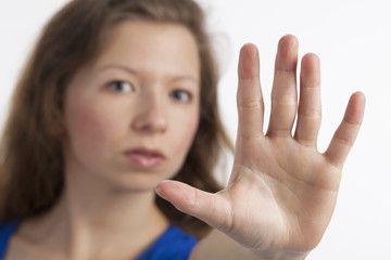 Obraz na płótnie Canvas Junge Frau mit zum Stopp erhobener Hand im Vordergrund