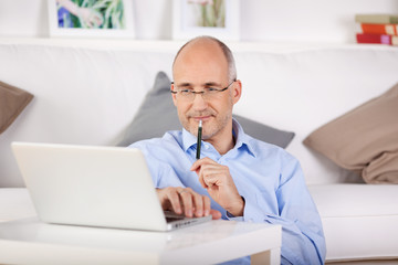 zufriedener mann sitzt zuhause am laptop
