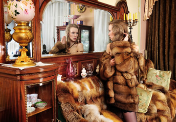 woman in fur coat  at the mirror in  Luxurious classical interio
